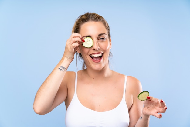 Mujer joven hermosa feliz que lleva a cabo rebanadas de pepino