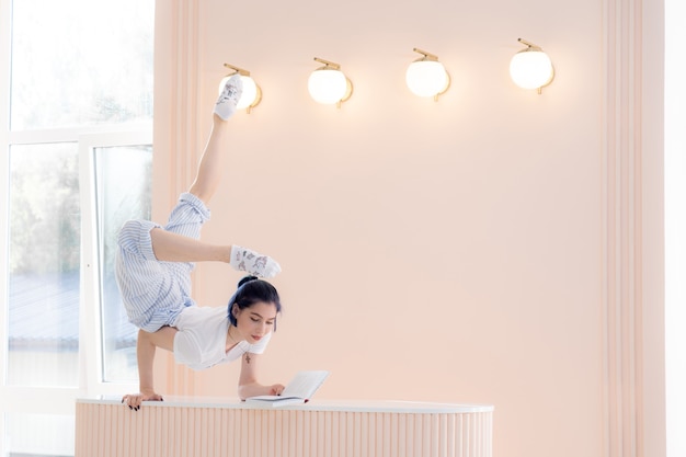 Mujer joven hermosa flexible que lee un libro en el escritorio en casa concepto de la creatividad de la individualidad ...