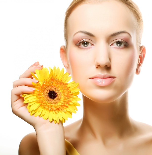 Mujer joven hermosa con la flor del gerber aislada en blanco