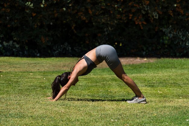 Mujer joven y hermosa haciendo gimnasia en el jardín de su casa en un día soleado dieta de yoga salud