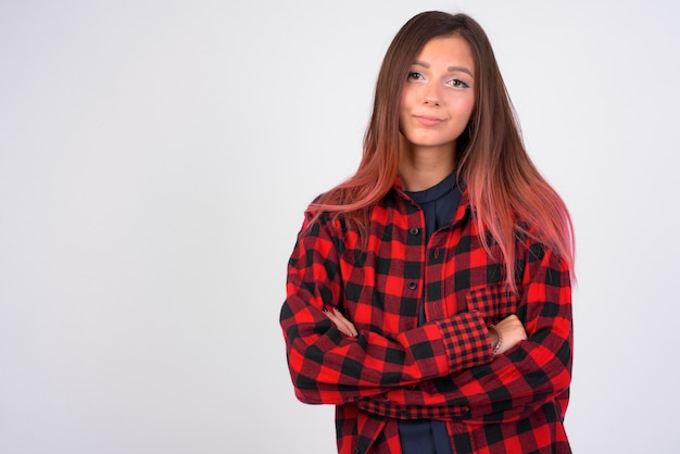 Mujer joven hermosa inconformista con los brazos cruzados contra la pared blanca