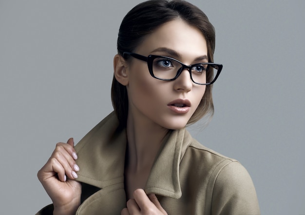 Mujer joven hermosa inconformista en moda abrigo y gafas