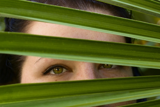 Mujer joven hermosa ojos verdes piel blanca hoja de palma verde retrato