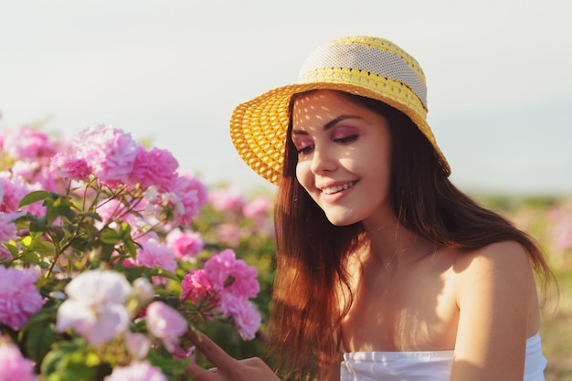 Mujer joven hermosa que presenta cerca de rosas en un jardín.