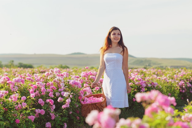 Mujer joven hermosa que presenta cerca de rosas en un jardín.