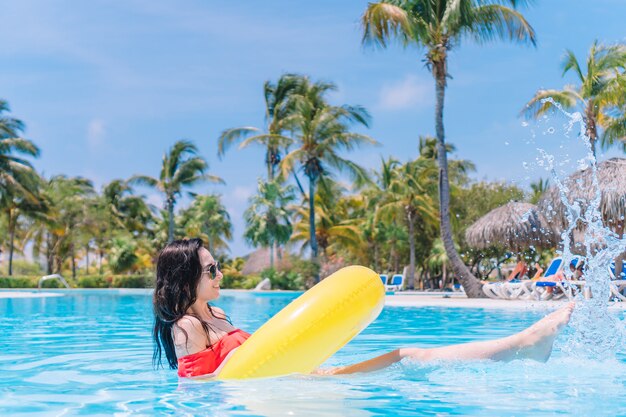 Mujer joven hermosa que se relaja en piscina.