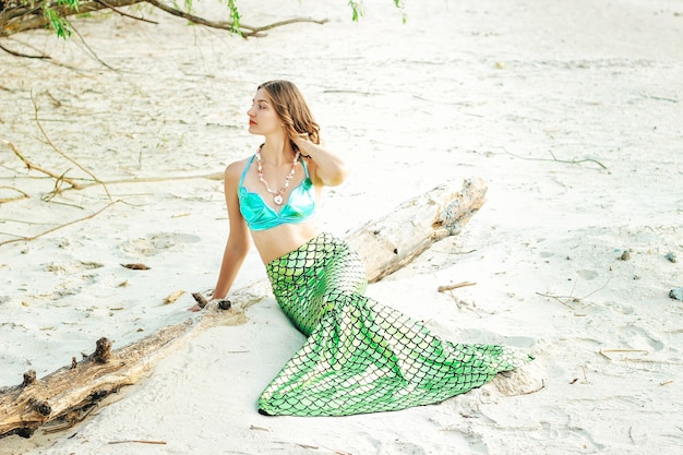 Mujer joven hermosa sirena de cerca de pie en la costa del mar. Cosplay de sirena.