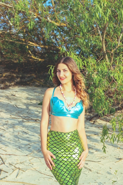 Mujer joven hermosa sirena de cerca de pie en la costa del mar. Cosplay de sirena.