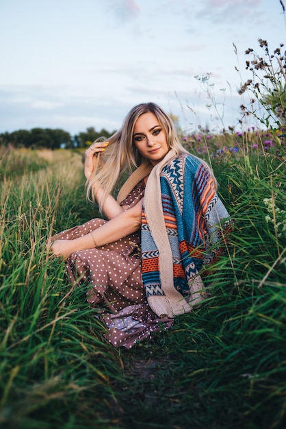 La mujer joven hermosa en un sombrero y un vestido camina en naturaleza en otoño.