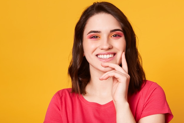 Mujer joven hermosa sonriente en camiseta rosada casual