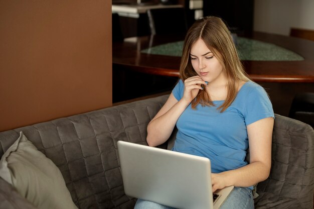 Mujer joven hermosa sonriente que usa la computadora en casa. Foto de alta calidad