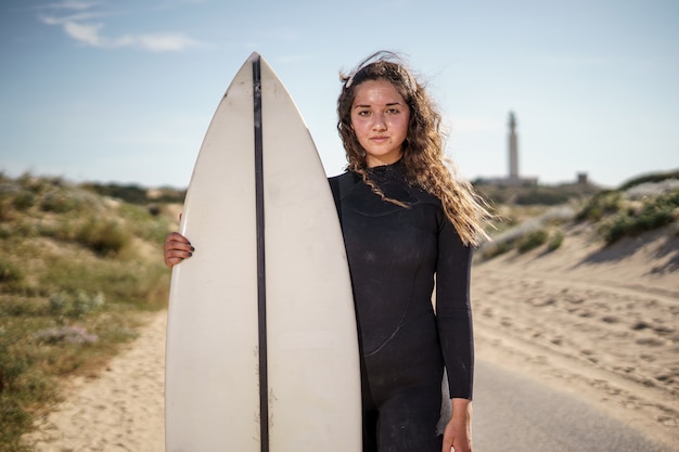 Mujer joven hermosa surfista en la playa al atardecer