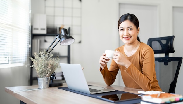 Mujer joven y hermosa trabaja para una computadora desde una casa con una computadora portátil