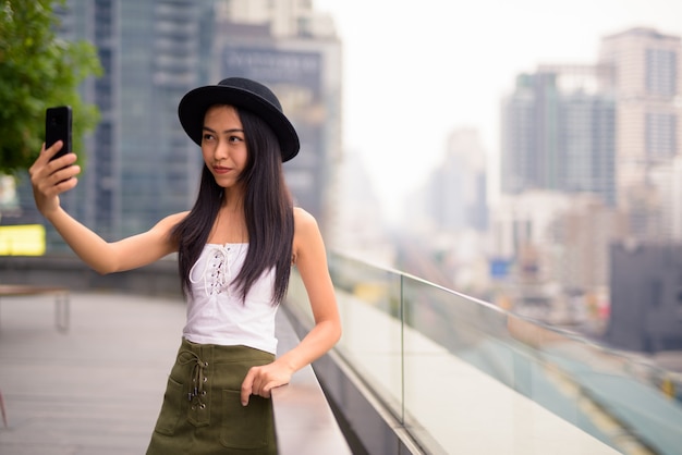 Mujer joven hermosa turista asiática tomando selfie contra vista de la ciudad