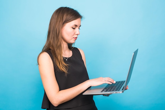 Mujer joven hermosa usando un teléfono inteligente contra un fondo azul