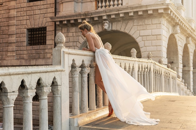 Mujer joven con hermoso vestido blanco caminando por una calle de la ciudad de Venecia