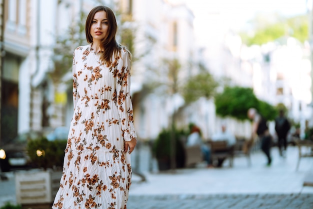 Mujer joven en un hermoso vestido posando en una calle de la ciudad. Hermosa chica disfruta de la primavera. Concepto de estilo de vida.