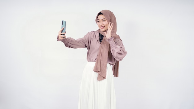 Mujer joven en hijab expresión feliz en videollamada aislado sobre fondo blanco.