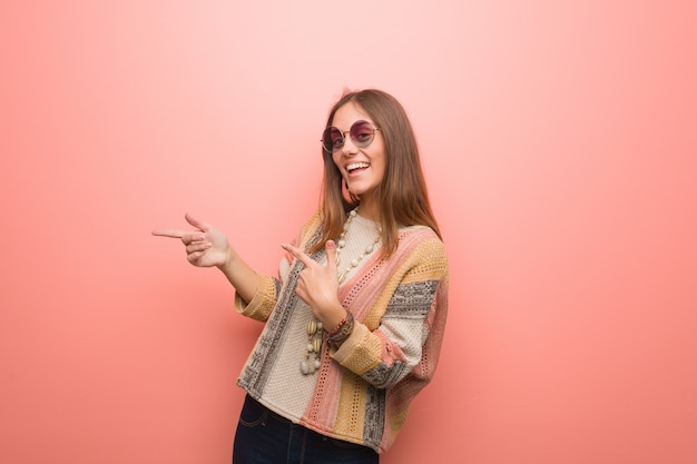 Mujer joven del hippie en el fondo rosado que señala al lado con el dedo