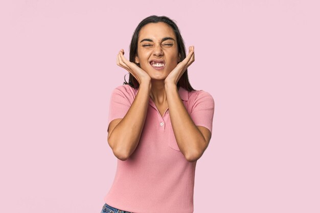 Mujer joven hispana cubriendo las orejas con las manos