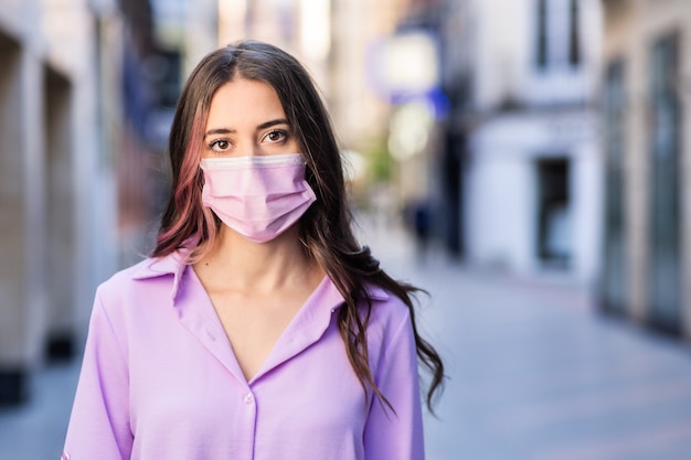 Mujer joven hispana con una máscara quirúrgica y distanciamiento social para la epidemia de covid19 Estilo de vida independiente y seguro Personas positivas caminando en la calle en España