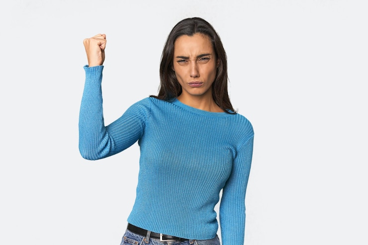Foto mujer joven hispana mostrando el puño a la cámara expresión facial agresiva