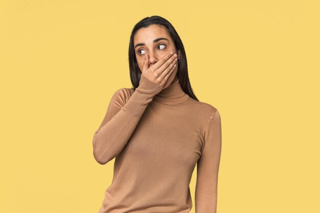 Foto mujer joven hispana pensativa mirando a un espacio de copia cubriendo la boca con la mano