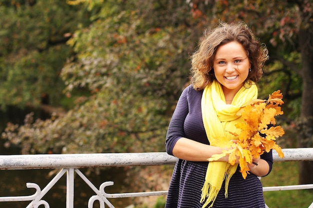 Mujer joven con hojas de otoño en el parque