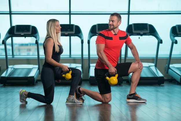 mujer joven, y, hombre, hacer, ejercicio, con, hervidor de agua, campana, en, el, gimnasio