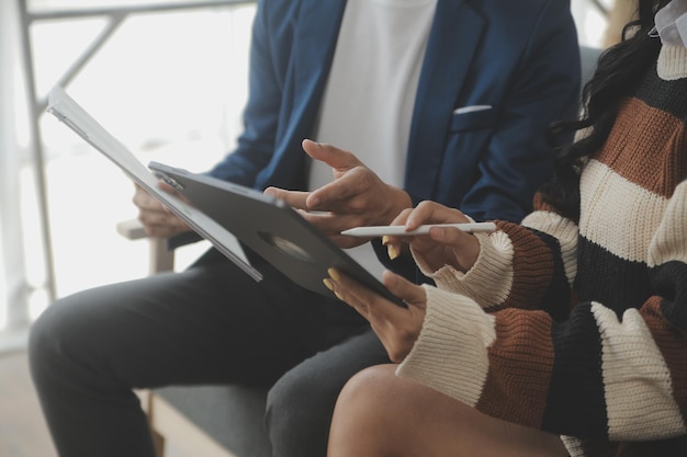 Mujer joven y hombre joven usando una computadora portátil mientras están sentados junto al sofá en casa