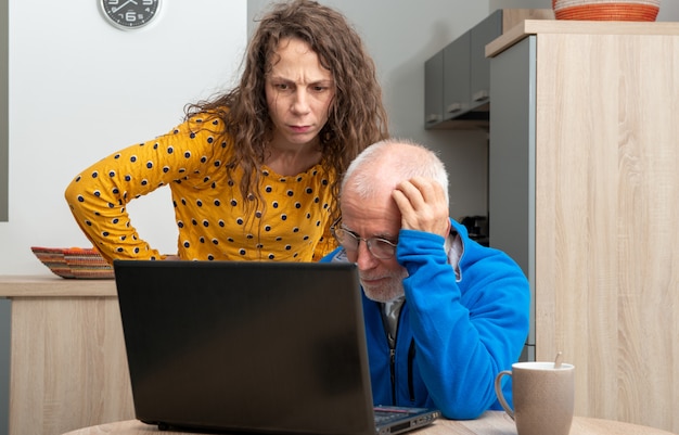 La mujer joven y el hombre mayor tienen problemas con la computadora portátil