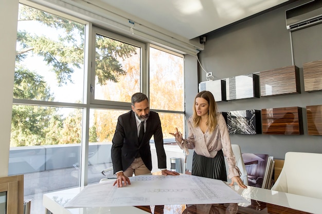 Mujer joven y hombre de negocios senior trabajando juntos en proyecto en la oficina moderna