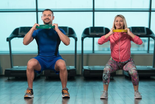 Foto mujer joven y hombres haciendo ejercicio con pesas en el gimnasio.