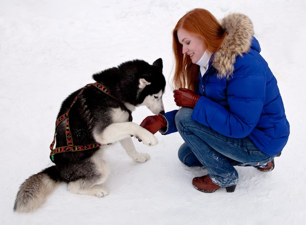 Mujer joven y husky en invierno