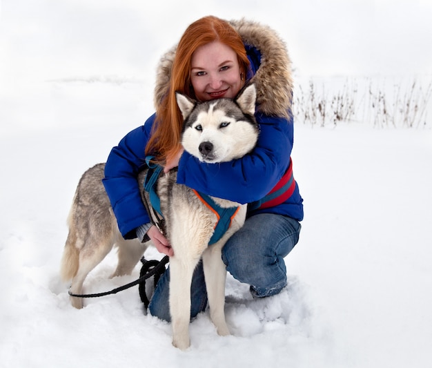 Mujer joven y husky siberiano en invierno