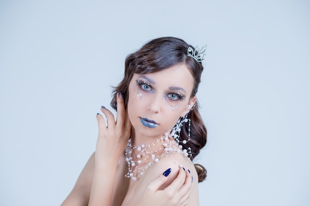 Mujer joven en imagen creativa con plata maquillaje artístico. Rostro de mujer hermosa.