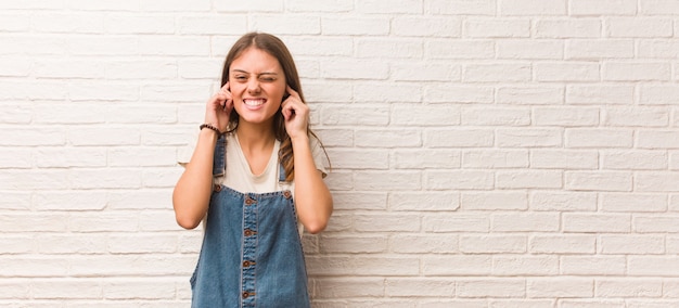 Mujer joven inconformista cubriendo las orejas con las manos