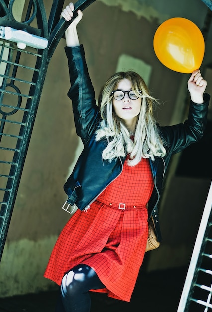 Mujer joven inconformista con globo en la ciudad, tiempo de primavera