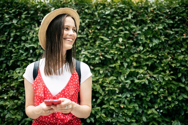 Foto mujer joven inconformista con teléfono inteligente mientras está de pie sobre fondo verde - estilo de vida influyente, vacaciones de verano y concepto de juventud - copie el espacio para el texto en el lateral