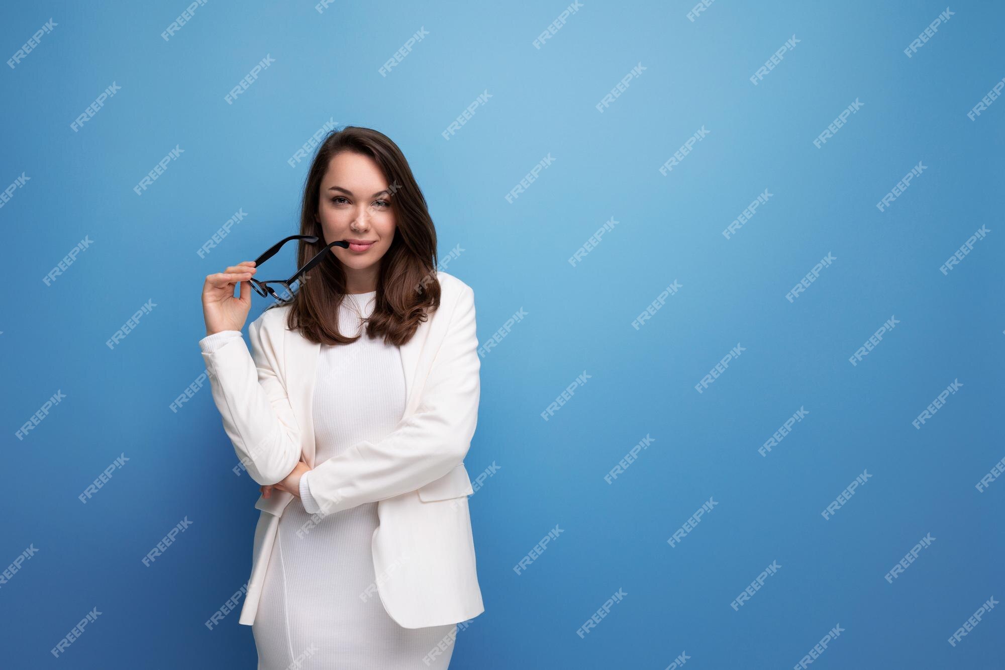 Mujer joven indignada vestido blanco de oficina mirando a la cámara desconcierto en el estudio Foto Premium