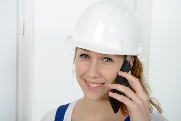 Foto mujer joven ingeniero con casco de seguridad hablando por teléfono