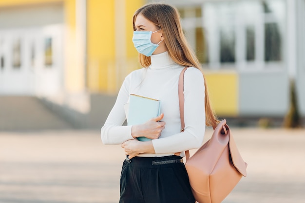 Una mujer joven en una institución educativa con una máscara anti-coronavirus