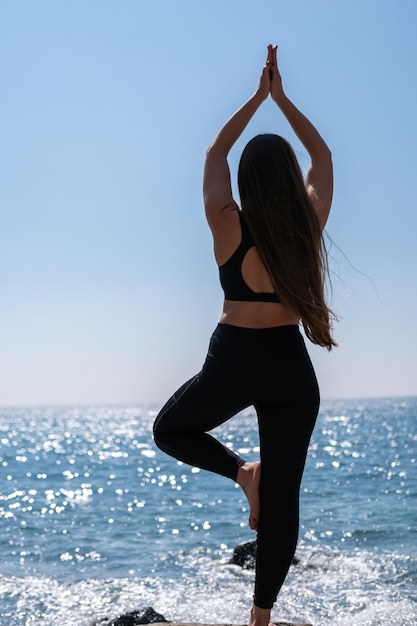 Mujer joven con instructor de fitness de pelo largo en leggings de ropa deportiva y tops estiramientos antes