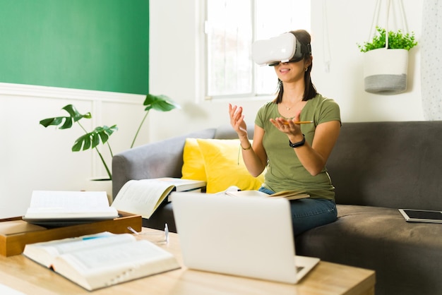 Mujer joven inteligente con gafas VR en casa respondiendo una pregunta de su profesor universitario durante una clase en línea