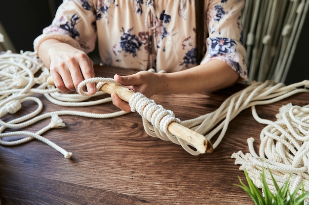 Mujer joven irreconocible haciendo una decoración de macramé en un espacio de trabajo