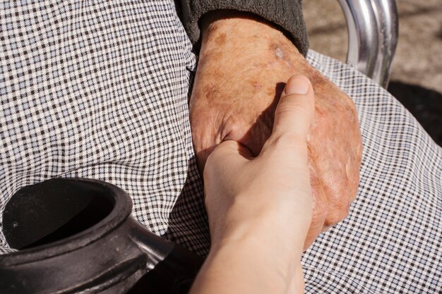 Mujer joven irreconocible con la mano de su abuela con cuidado. Amor al concepto de personas mayores. Personas con discapacidad en el estilo de vida de hogar de ancianos. Casa de retiro para personas en situación geriátrica.