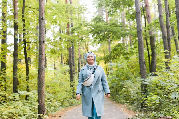 Mujer joven islámica con hijab de pie en el fondo del parque de otoño. Chica musulmana árabe moderna.