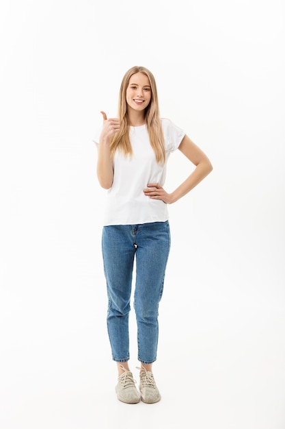 mujer joven en jeans mirando a la cámara dando un pulgar hacia arriba del éxito