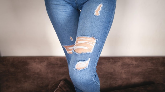 Mujer joven en jeans rasgados modernos en casa.