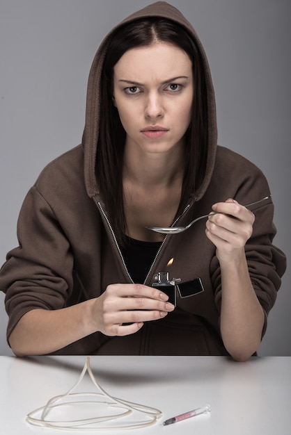 Mujer joven con jeringa y drogas.